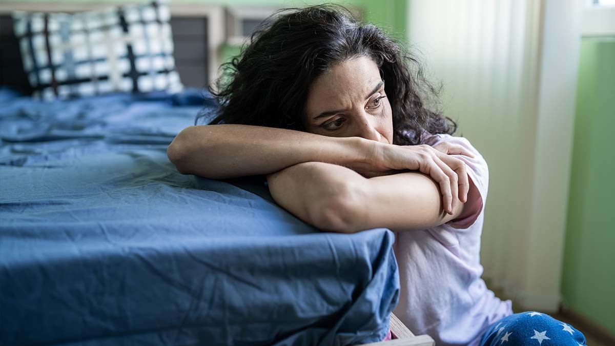 Worried women sitting at the end of her bed